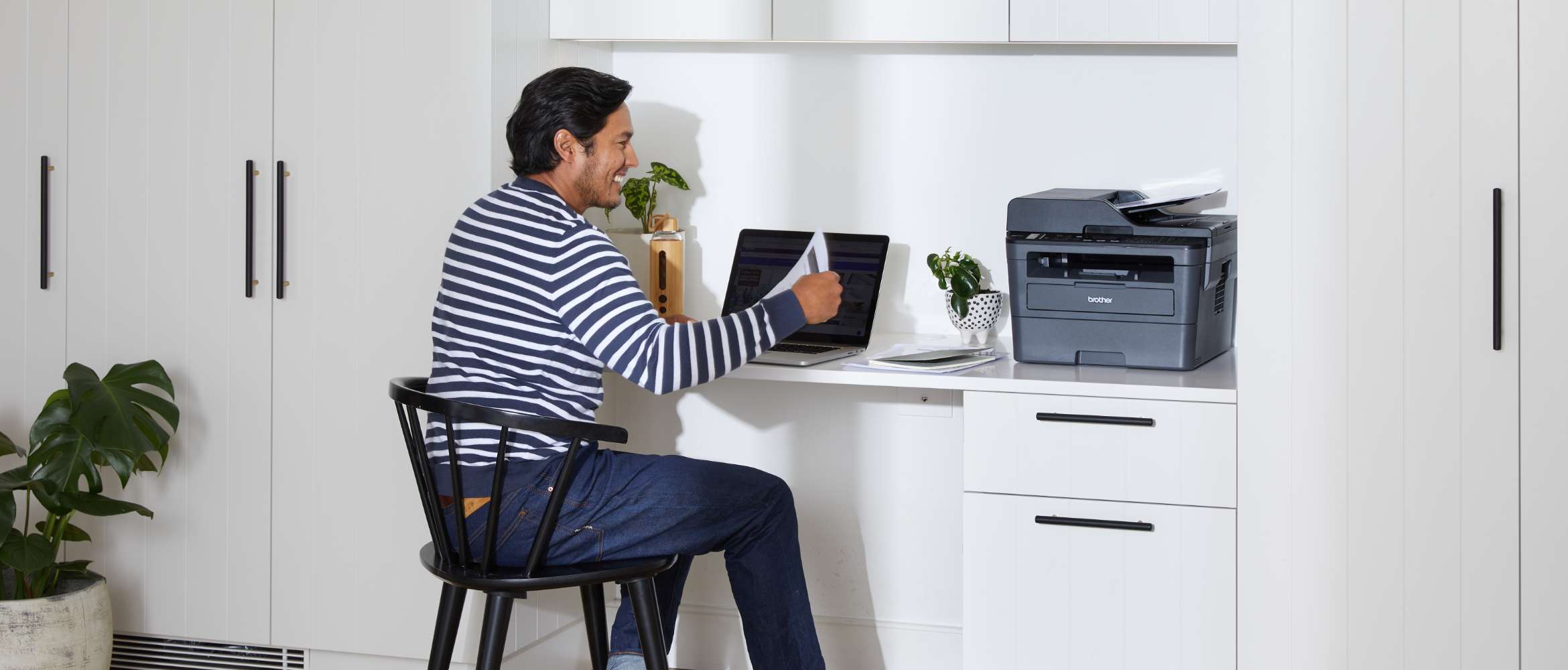 Man sitting behind the desk with notebook and Brother printer