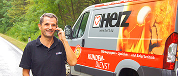 Serwisant Herz rozmawiający przez telefon obok pojazdu Herz