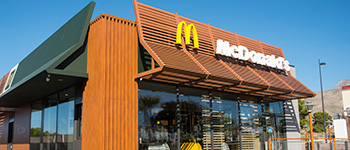 Budynek Mcdonalds z logo przed budynkiem, w tle błękitne niebo