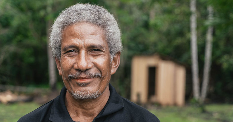 Close up of a male smiling in an outdoor setting with jungle surroundings