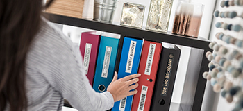 Picture of woman putting a labelled file on a bookcase