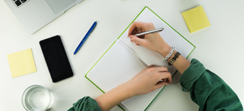 taking notes on a desk with mobile phone visible