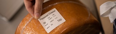 Deli price label being applied to a bag containing slices of cheese